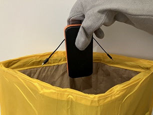 A portable powerbank being placed inside an AvSax thermal containment bag